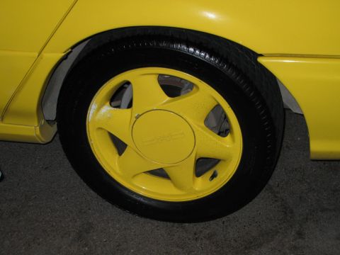 2002 Ford Taurus - Close-up of a yellow car's wheel and tire, showing the five-spoke rim design.