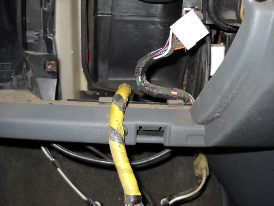 Close-up of a vehicle's interior wiring harness with yellow tape and connectors