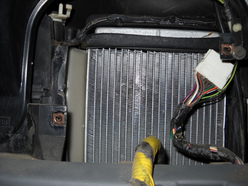 Heater core with visible fins and a black wiring harness with multiple colored wires connected to a white connector