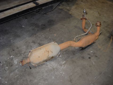 1993 Ford C-150 (Centurion Conversions) - This is an exhaust system part, likely a catalytic converter with associated piping and an oxygen sensor, shown on a concrete floor.