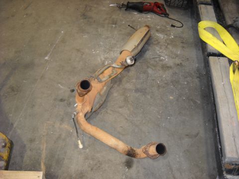 1993 Ford C-150 (Centurion Conversions) - Exhaust system part removed from a vehicle, lying on a workshop floor.