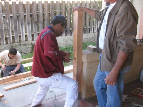 1968 Ford Mustang - Men are engaged in construction work, assembling wooden posts and lumber in an outdoor setting.