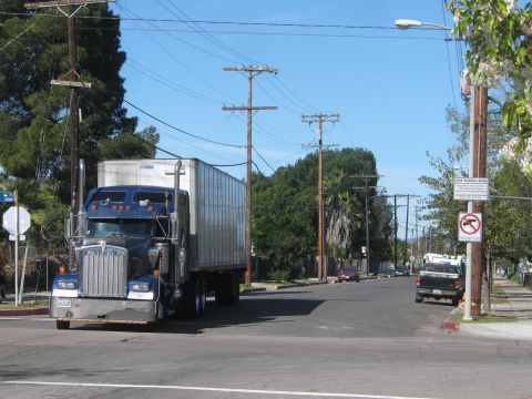 1968 Ford Mustang - A blue semi-truck and trailer drives down a street lined with power poles and trees.