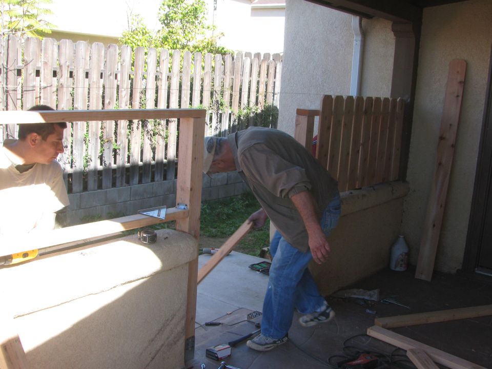 Two men constructing a wooden frame outdoors