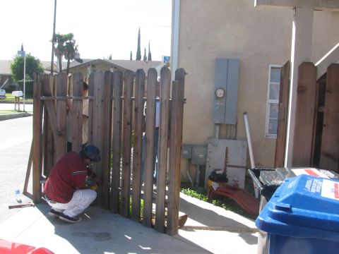 1968 Ford Mustang - Several people are repairing a wooden fence in front of a building.