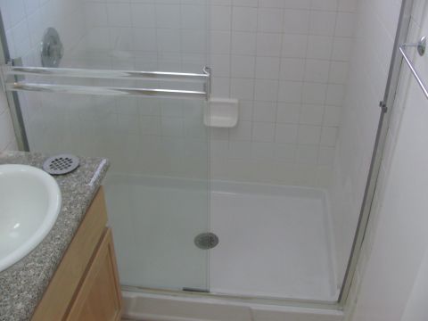 1968 Ford Mustang - A bathroom scene a sink and a shower stall with white tiled walls.