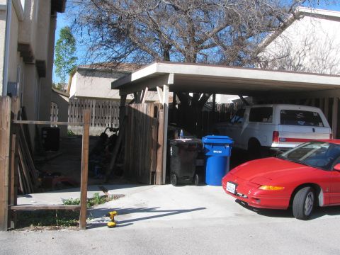 1968 Ford Mustang - Two vehicles are parked under a carport, with a red sports car in the foreground.
