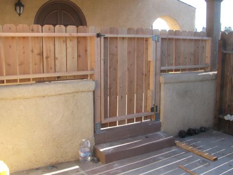 1968 Ford Mustang - A wooden fence and gate stand on a patio next to a stucco wall, with a water bottle visible.