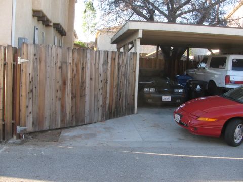 1968 Ford Mustang - A black coupe is parked under a carport next to a white SUV and a red car.