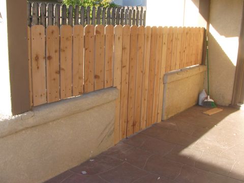 1968 Ford Mustang - A wooden fence borders a patio area, with cleaning supplies nearby.