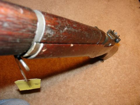 2003 Ford Crown Victoria - A close-up view of a rifle's wooden stock and metal components, with a yellow tag hanging from a sling swivel.
