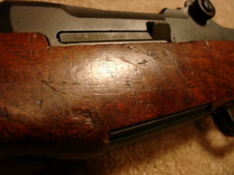 2003 Ford Crown Victoria - Detail of the aged and scratched wooden stock of a firearm.