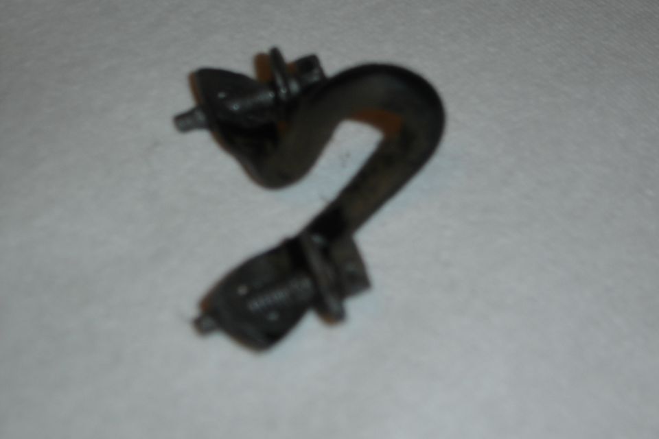 Blurry close-up of a dark metal automotive bracket with bolts on white cloth