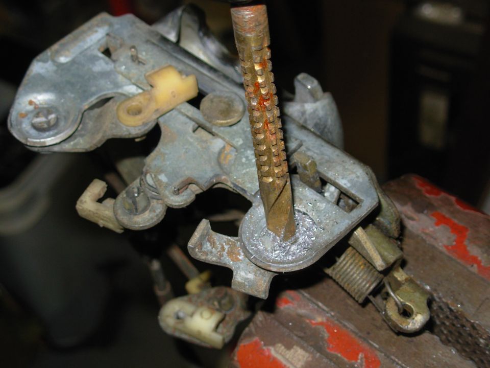 Because this latch has failed to release the door more than once due to a sticking lock mechanism, it will be modified so the inside handle is failsafe, and so operating the inside handle unlocks the door.  The auto unlock lever's pivot has to be removed so another lever can be added.

The latch's original functions will be left UNmodified, so it will be easy to revert to the factory configuration & function simply by moving the operating rod back to the factory inside release lever.  The new lever can remain (unused) without affecting the latch's performance or reliability.