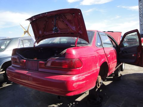 1993 Ford Taurus - A red sedan sits with its trunk and driver door ajar, missing its wheels.