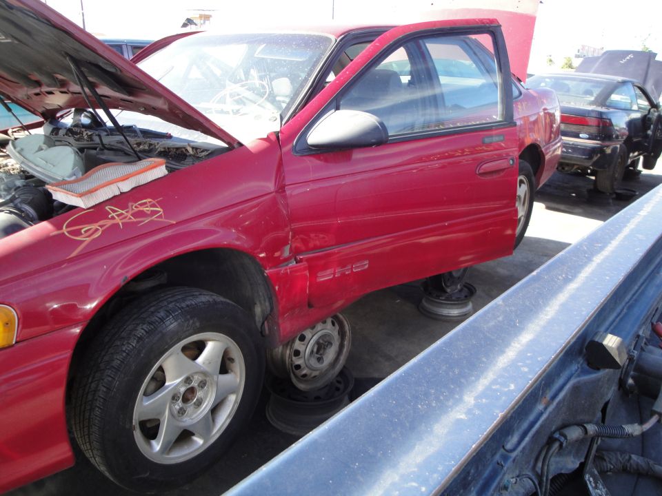 red sedan with SHO badge, hood and door open, missing wheels, another car in background