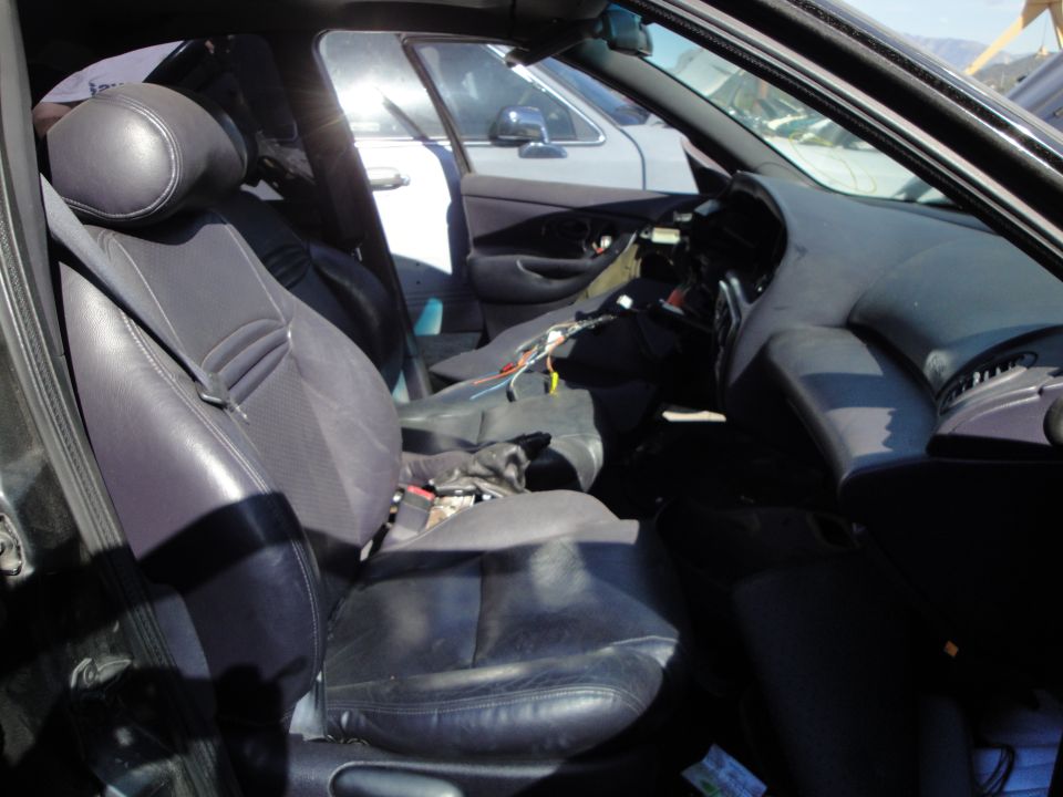 Interior view of a 1993 Ford Taurus showing front seats, dashboard, and exposed wiring. Another vehicle is visible through the passenger window