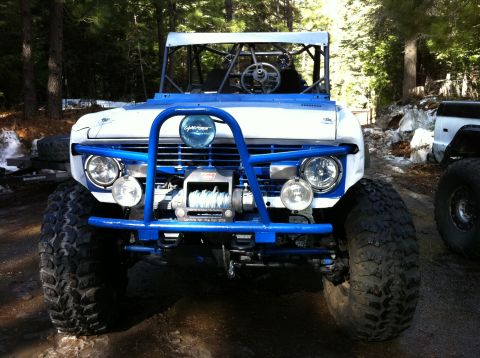 1989 Ford Bronco - This heavily modified SUV features a prominent blue front bumper and winch, suggesting it's built for off-road use.