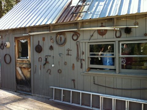 1989 Ford Bronco - A collection of antique tools and metal objects adorn the exterior wall of a weathered shed.