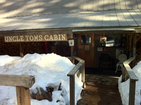 1989 Ford Bronco - The entrance to Uncle Tom's Cabin is partially obscured by large snowdrifts, with firewood stacked to the left.