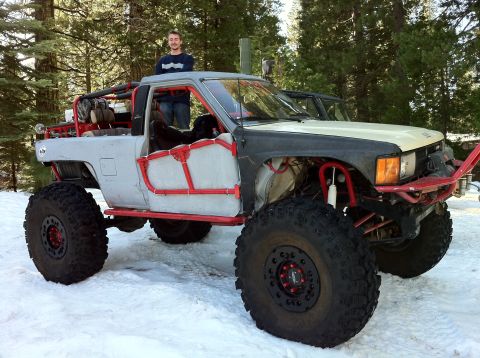 1989 Ford Bronco - A heavily modified pickup truck with oversized tires and a custom roll cage is parked in a snowy, wooded area.