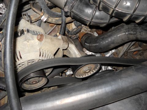1993 Ford C-150 (Centurion Conversions) - Close-up view of the engine bay, focusing on the alternator and belt system.