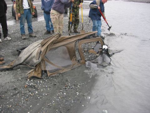 1994 Ford Bronco - A group of people observe a damaged vehicle frame and soft top in shallow, murky water.