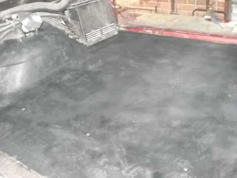 1993 Ford C-150 (Centurion Conversions) - The interior floor of a vehicle, showing exposed wiring and ducting, with a brick wall in the background.