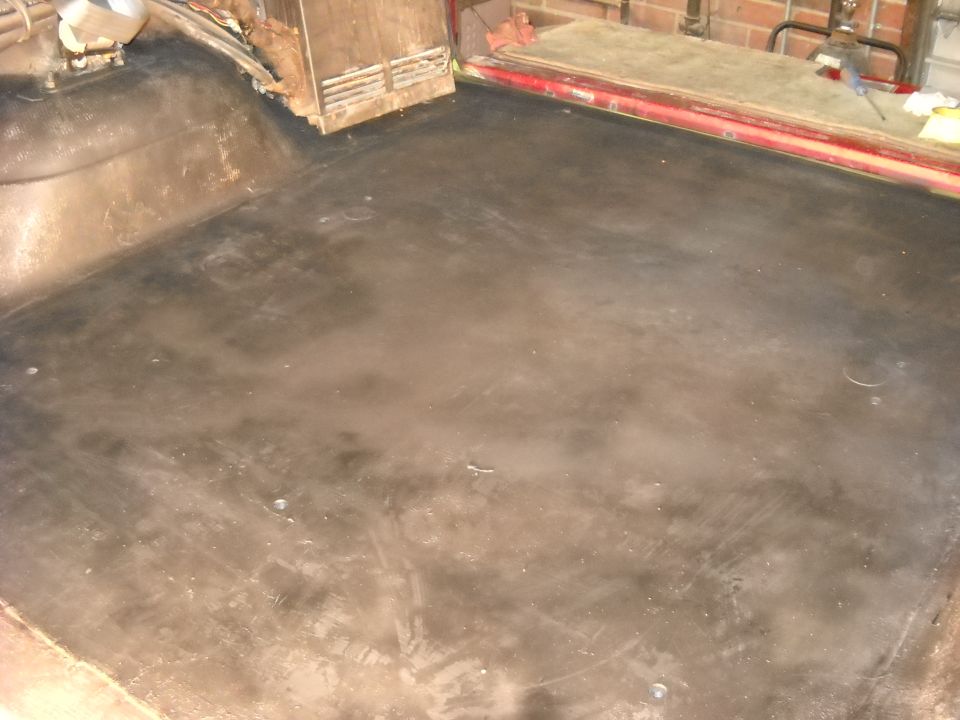 Vehicle interior floor with black matting, showing the rear cargo area and part of the passenger side