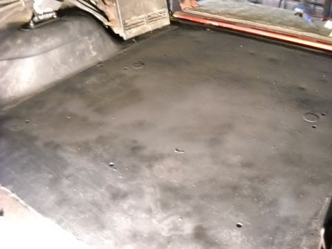 1993 Ford C-150 (Centurion Conversions) - The dark, flat surface of the vehicle's interior floor is visible, with some scattered holes and a slightly worn appearance.