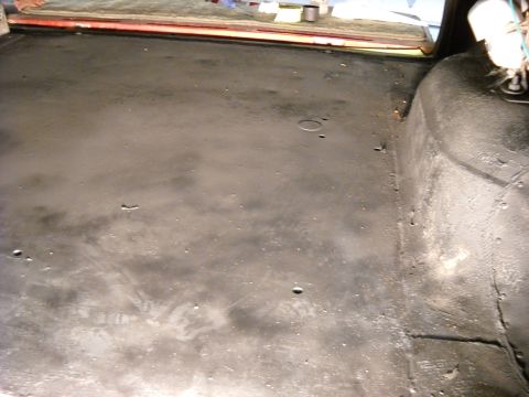 1993 Ford C-150 (Centurion Conversions) - The cargo area floor of a vehicle shows signs of wear and tear, with scuff marks and a circular indentation visible.