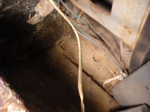 1993 Ford C-150 (Centurion Conversions) - The image shows a close-up view of the interior floor of a vehicle, revealing dirt, debris, and exposed wiring.