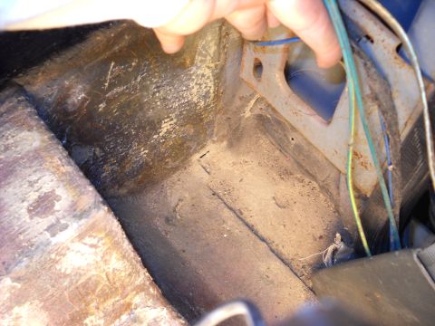 1993 Ford C-150 (Centurion Conversions) - Close-up view of the interior floor pan of a vehicle, showing wear and tear.