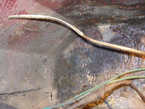 1993 Ford C-150 (Centurion Conversions) - Close-up of a corroded vehicle floor with wiring harness visible.