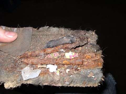 1993 Ford C-150 (Centurion Conversions) - A close-up view reveals heavily rusted metal components intertwined with dirty, matted fabric and debris.