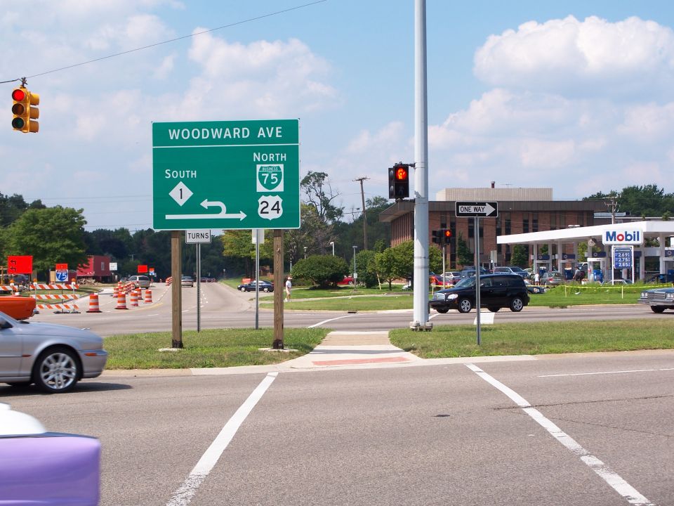Street signs for Woodward Ave, I-75, and I-24 at an intersection with a Mobil gas station