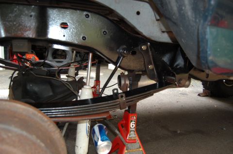 1994 Ford Bronco - Close-up of a vehicle's undercarriage, showing leaf springs and suspension components supported by red jack stands.