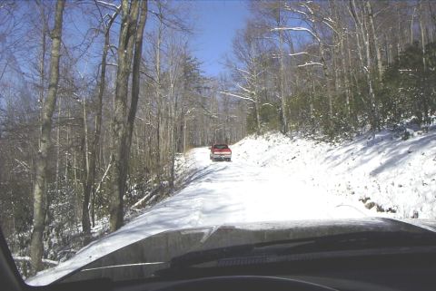 1995 Ford Bronco - Two trucks travel down a snowy forest road.