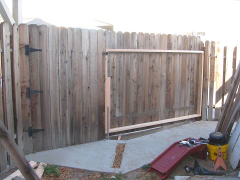1968 Ford Mustang - A wooden fence with a gate opening is visible, along with a red slide and construction materials.