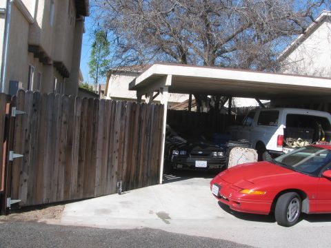 1968 Ford Mustang - Three vehicles are parked under a carport on a sunny day.