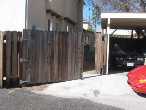 1968 Ford Mustang - A black car, likely from the late 1980s, is parked under a carport next to a red car.