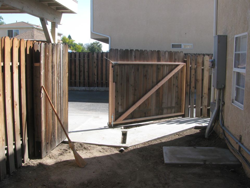 Wooden backyard gate and fence with a broom leaning against it