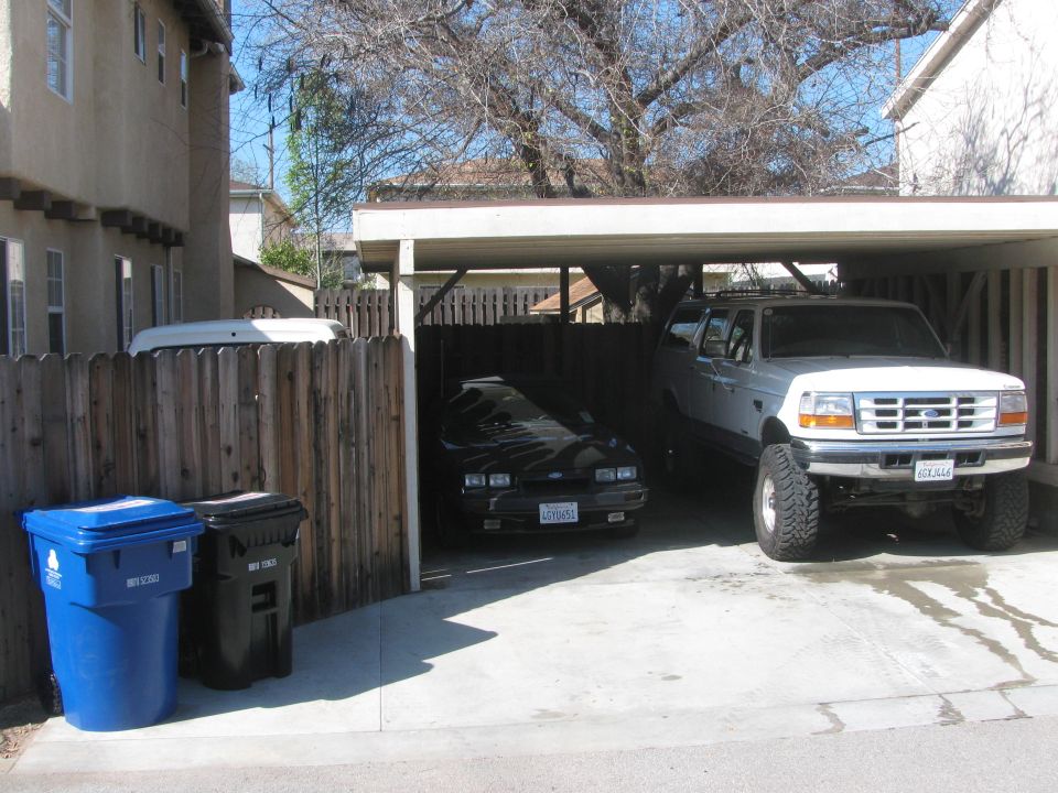 Black car and white pickup truck parked under a carport