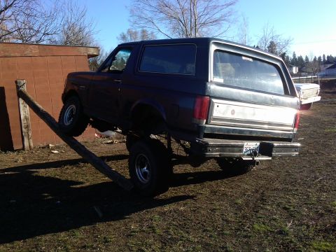 1988 Ford Bronco - This lifted Ford Bronco is positioned with its front tire on a log, creating an uneven stance.