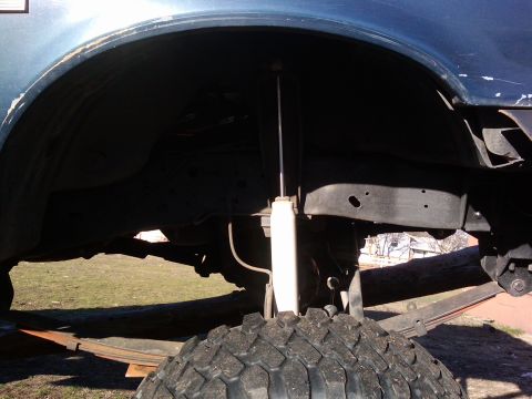 1988 Ford Bronco - Close-up view of a vehicle's rear suspension system, including the tire, leaf springs, and shock absorber.