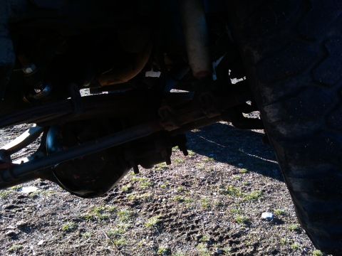 1988 Ford Bronco - The underside of a vehicle shows its suspension components and rear axle assembly.