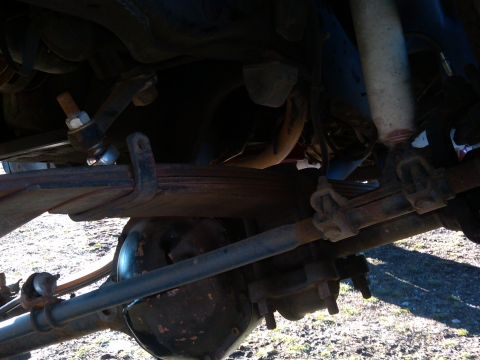 1988 Ford Bronco - Close-up of vehicle suspension components, including leaf springs and a shock absorber.