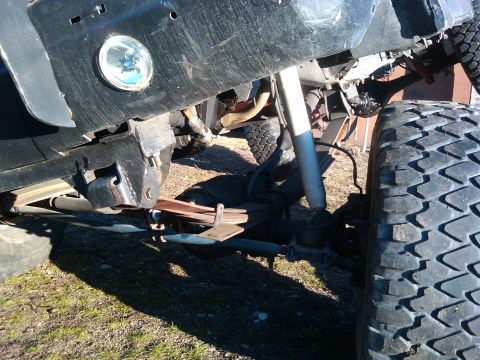 1988 Ford Bronco - Close-up view of the suspension system and large tire of an off-road vehicle.