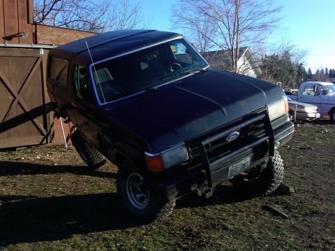 1988 Ford Bronco - 1988 Ford Bronco demonstrating suspension flex with one wheel elevated on a rock.