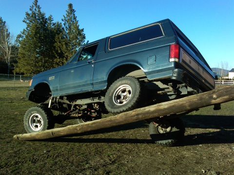 1988 Ford Bronco - A modified Ford Bronco navigates an obstacle, demonstrating its off-road capabilities.